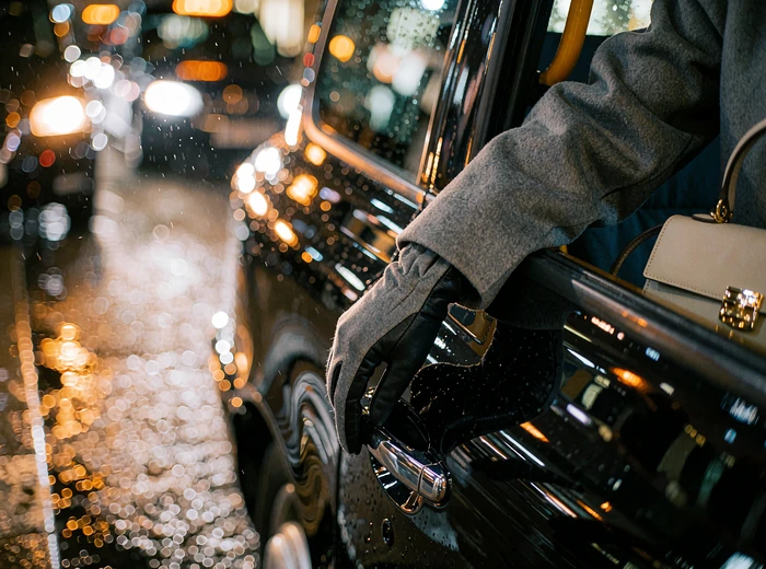 Close view of a woman's gloved hand on a taxi door handle at night in Chicago