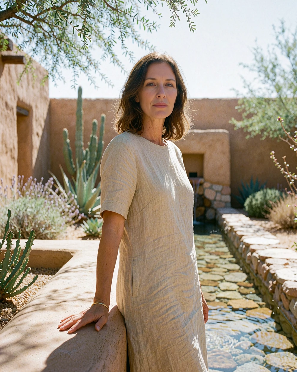 Woman in a sand-coloured linen dress standing in an adobe-walled Scottsdale resort courtyard