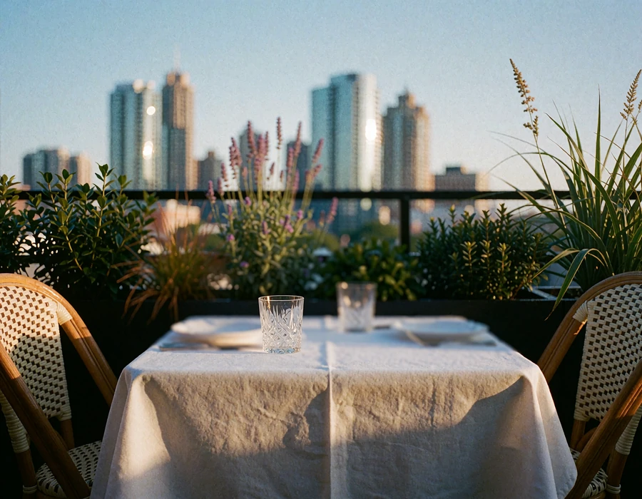 Empty two-person terrace table set with white linen and crystal glasses overlooking the Atlanta skyline